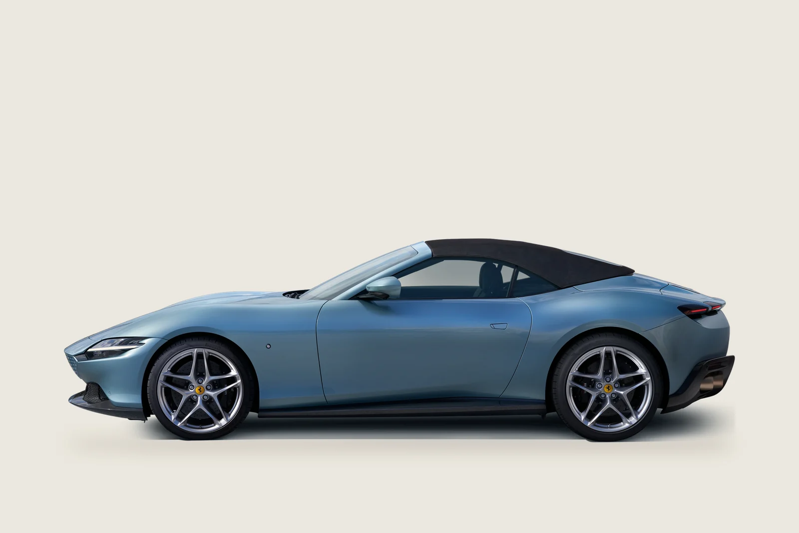 White Ferrari Roma Spider with a blue soft top seen from the side